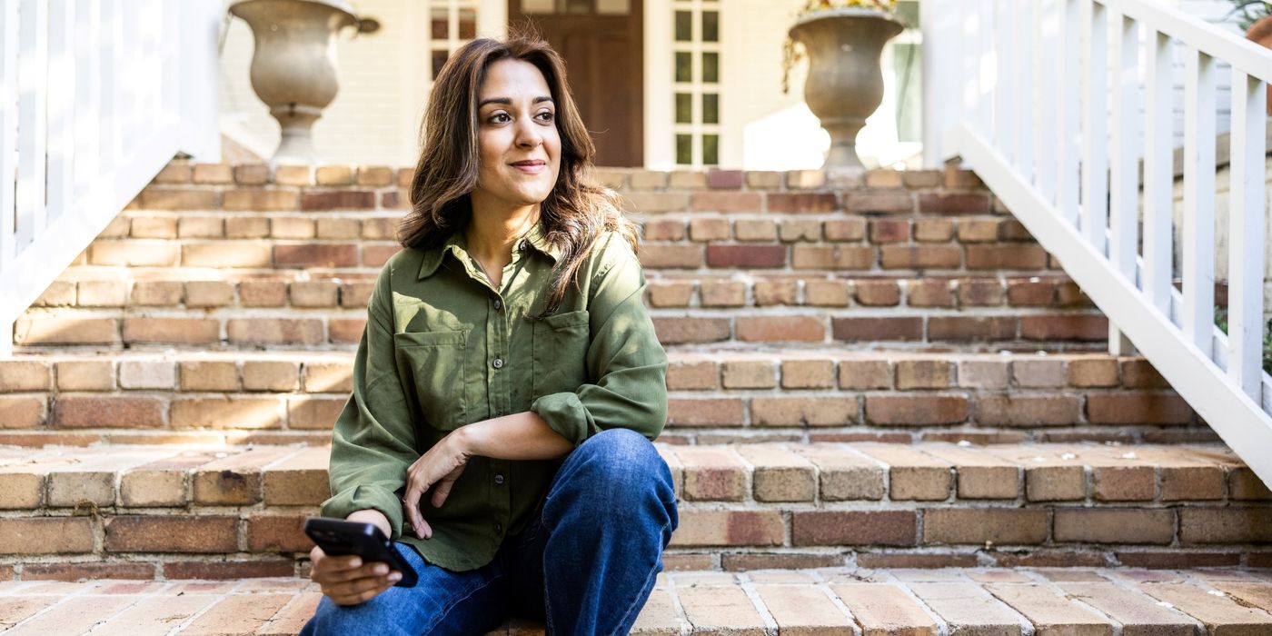 Woman with phone in front of a suburban house