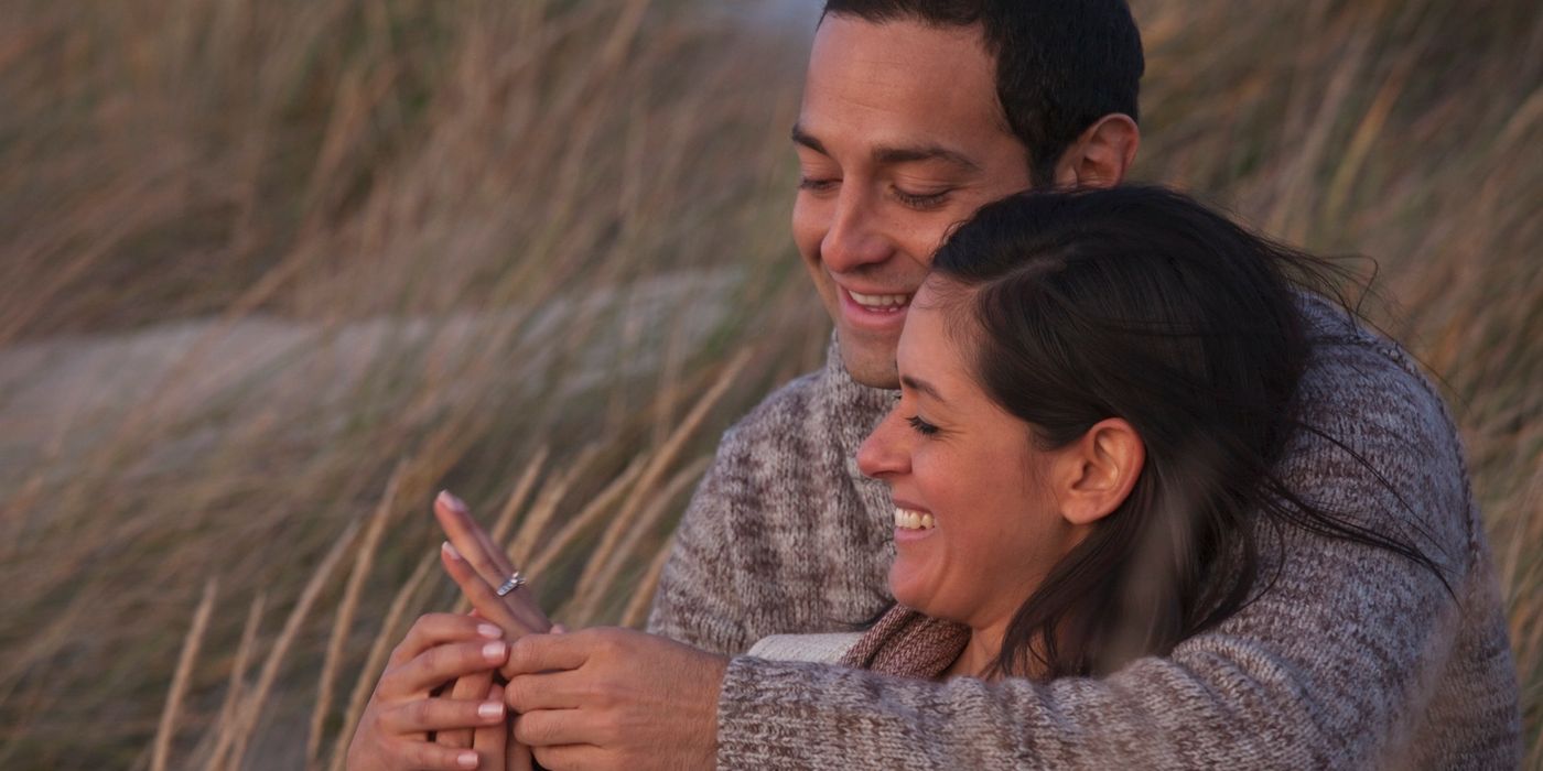 Couple sitting together smiling looking at an engagement ring