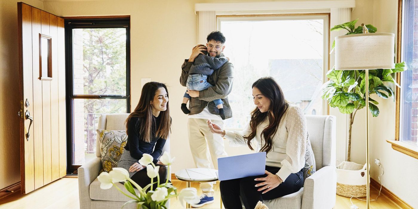 Wide shot of family discussing home for sale with real estate agent