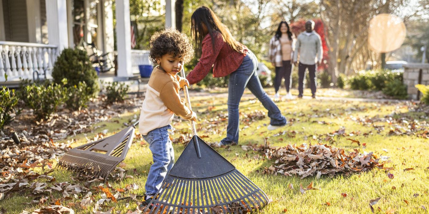Children raking leaves in front yard of home