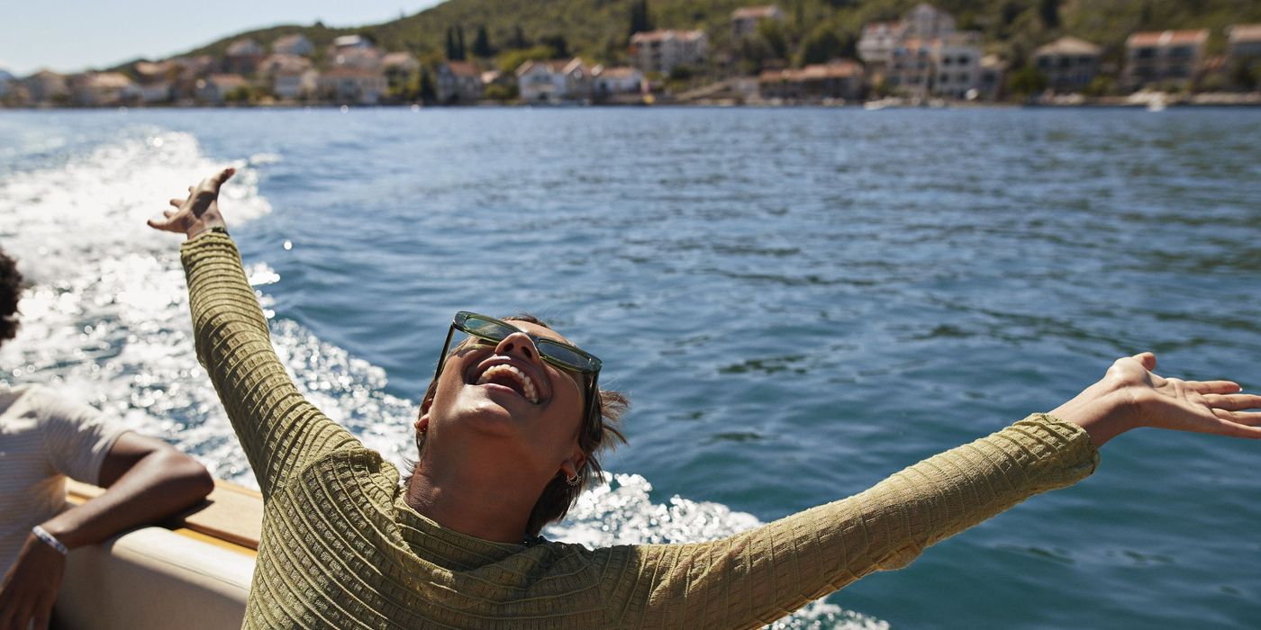 Happy woman with arms raised in motorboat