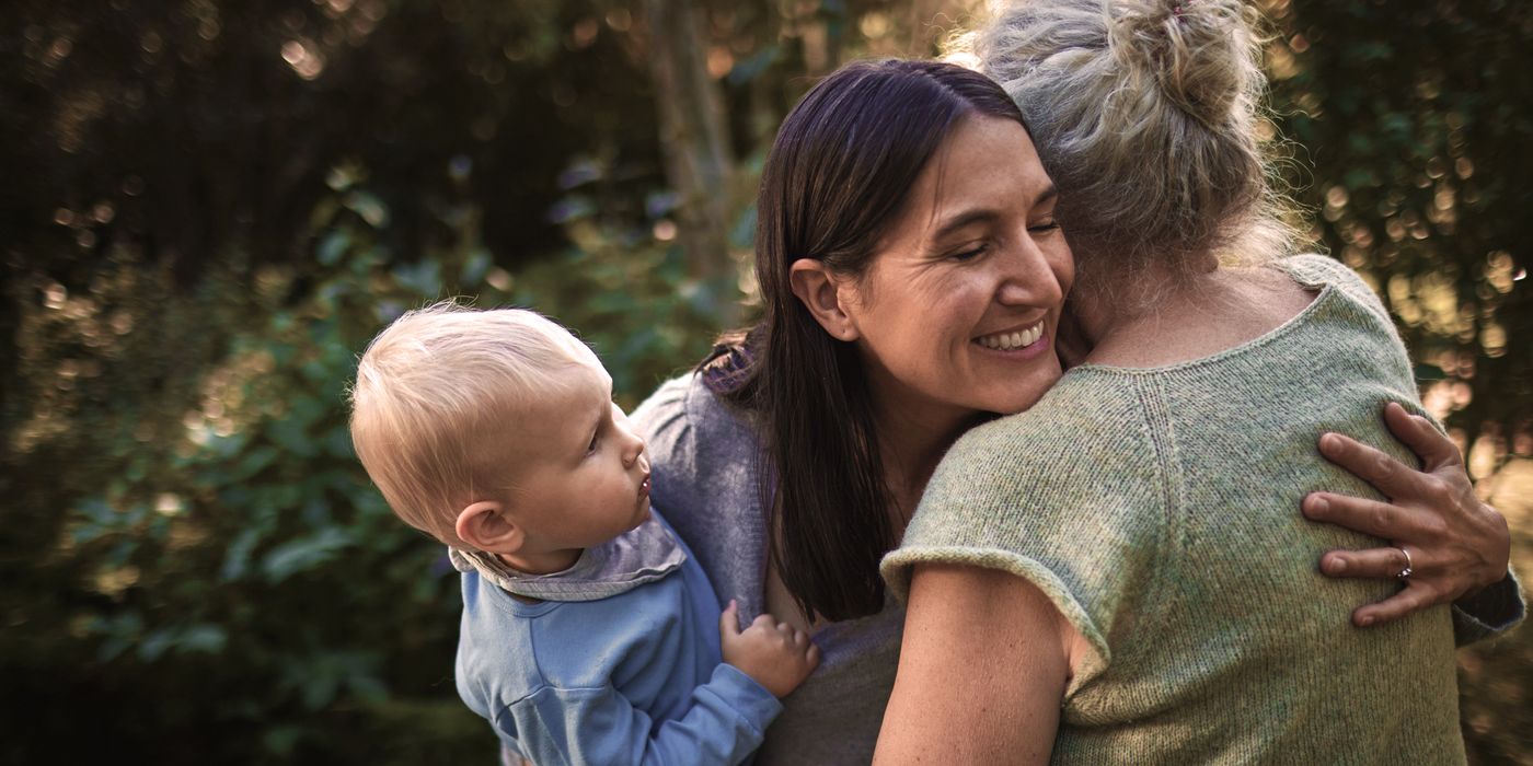 Happy woman with baby boy hugging senior mother in garden