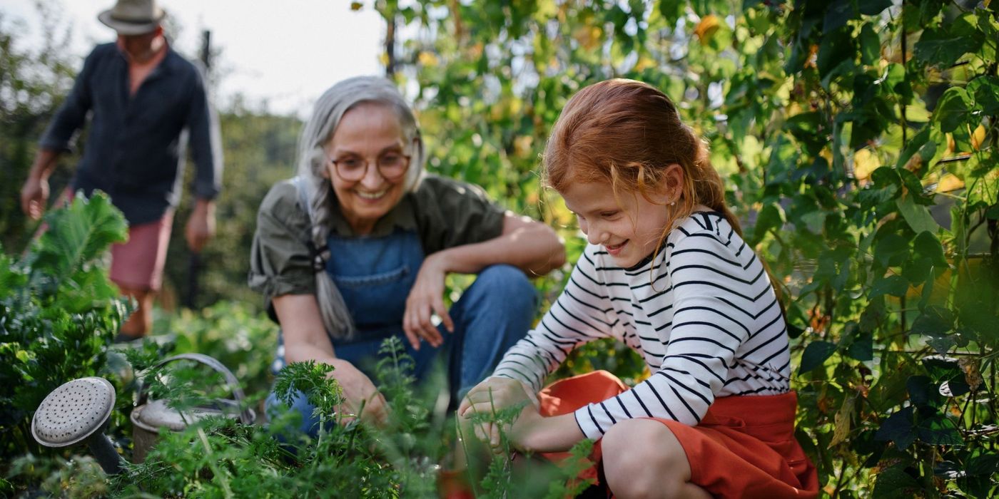 Grandmother with granddaughter working in garden together 