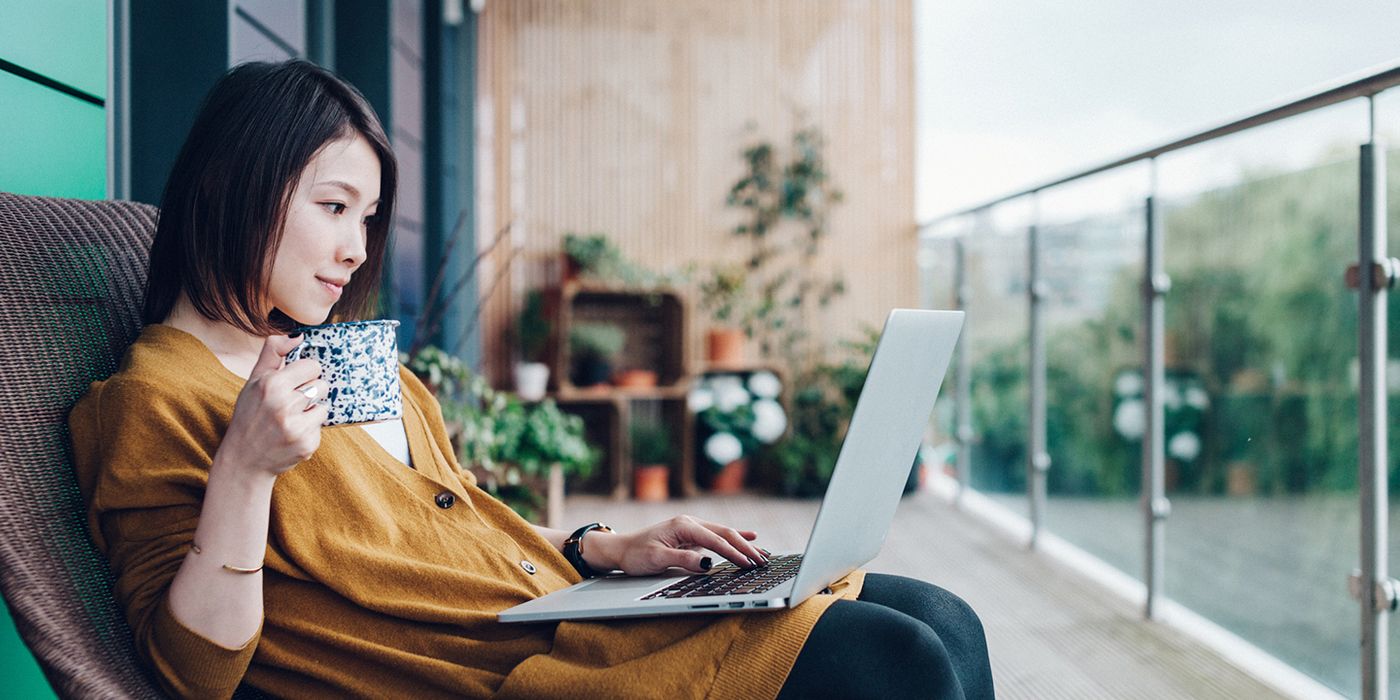 Woman checking her credit report on her laptop from her balcony