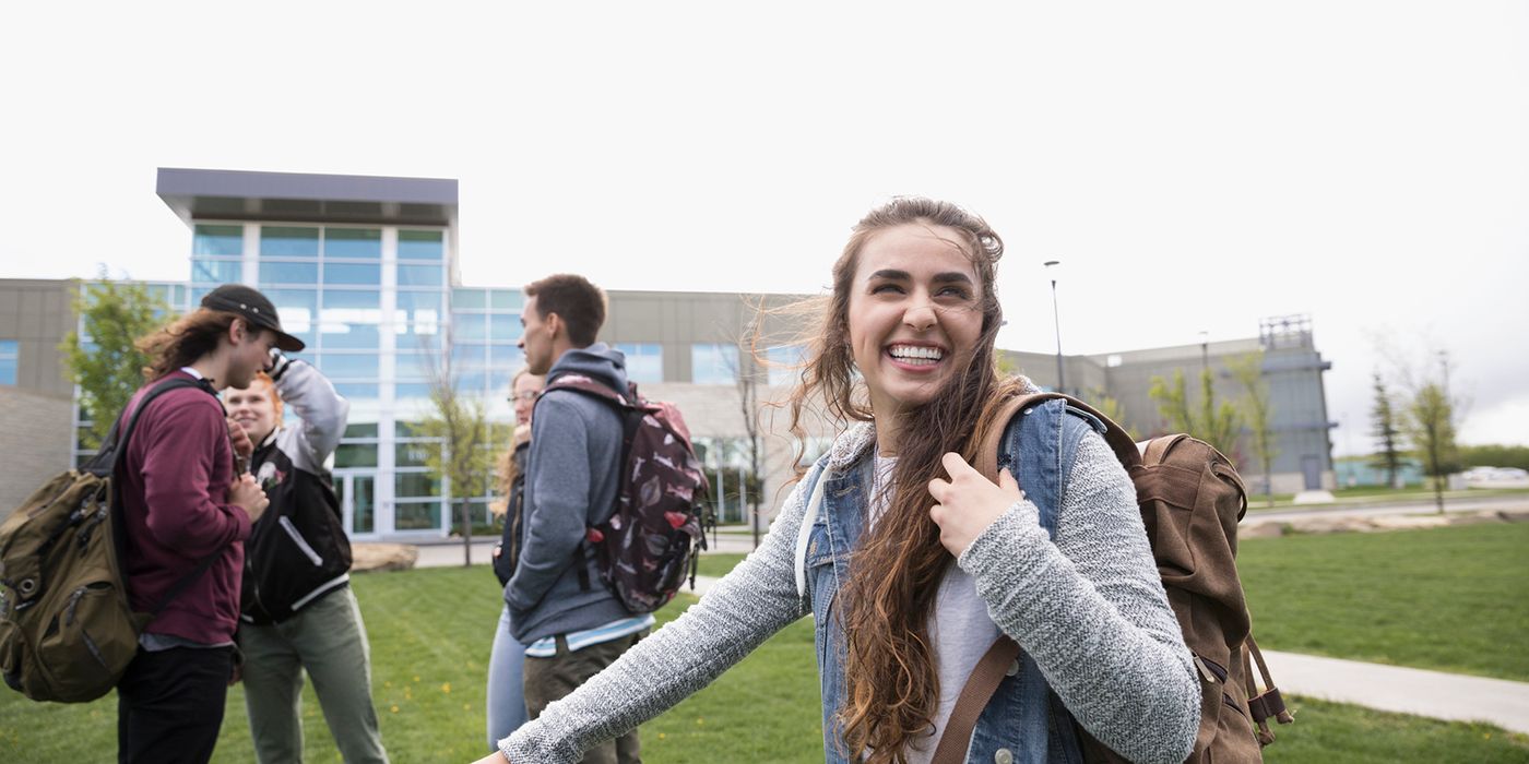 Young female college student smiling and walking on campus.