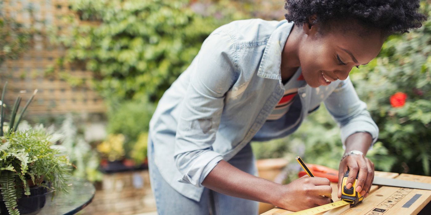 Young woman measures wood for renovation project.