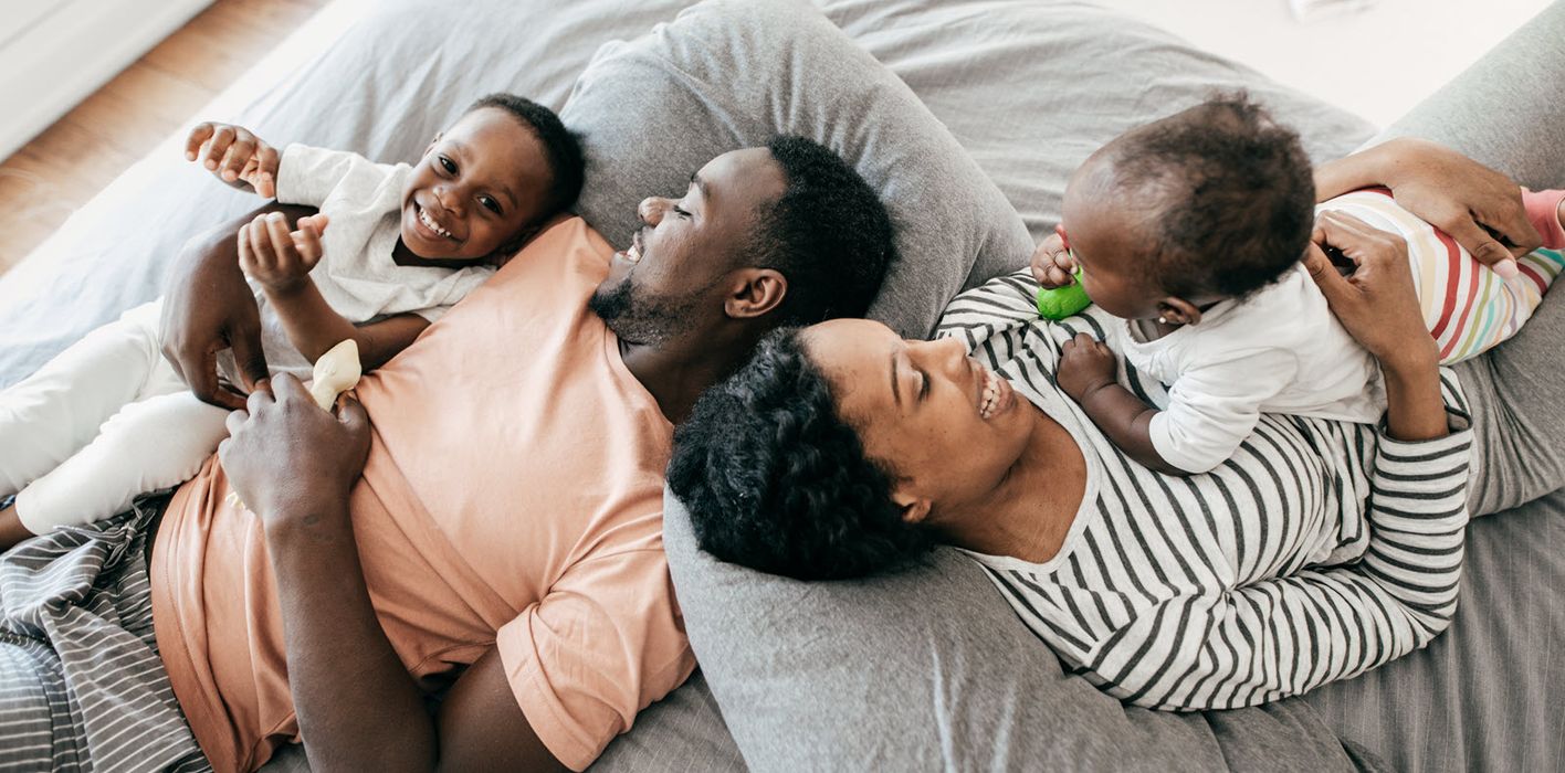 Couple lying on a bed with their kids