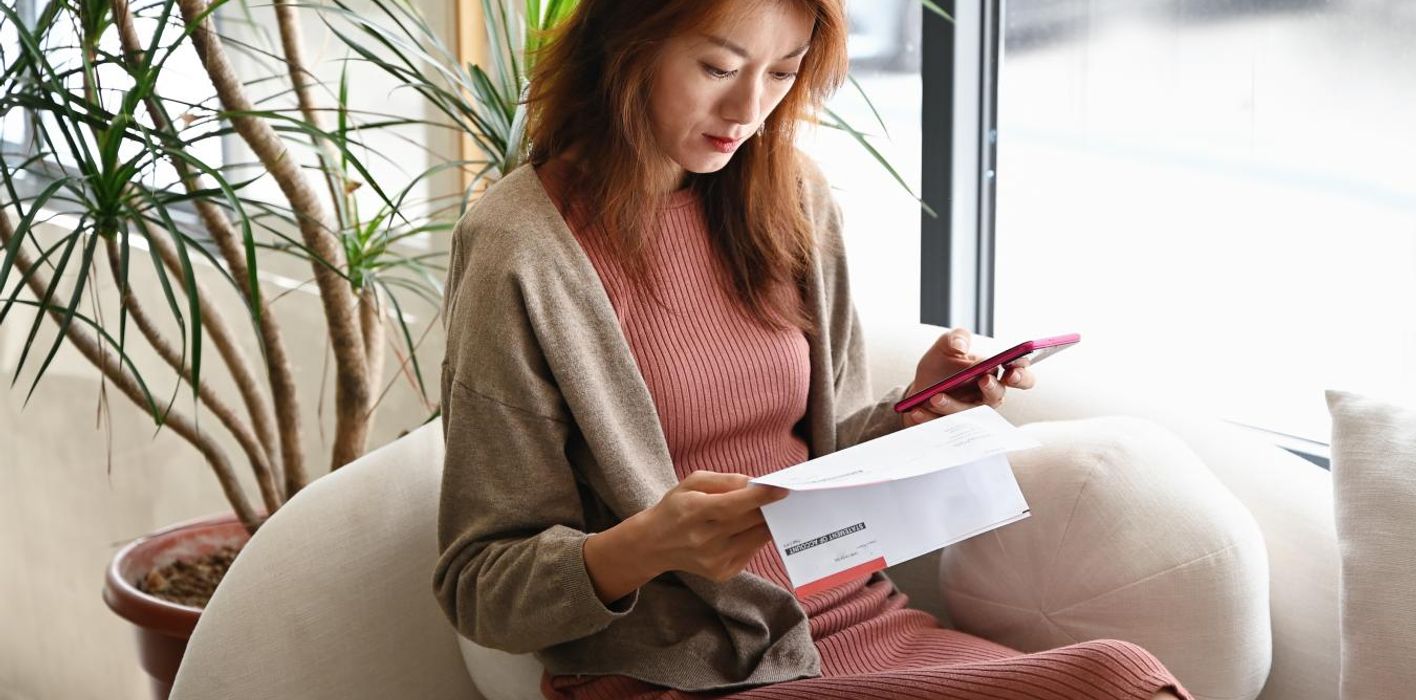Woman checking her bank statements on a sofa