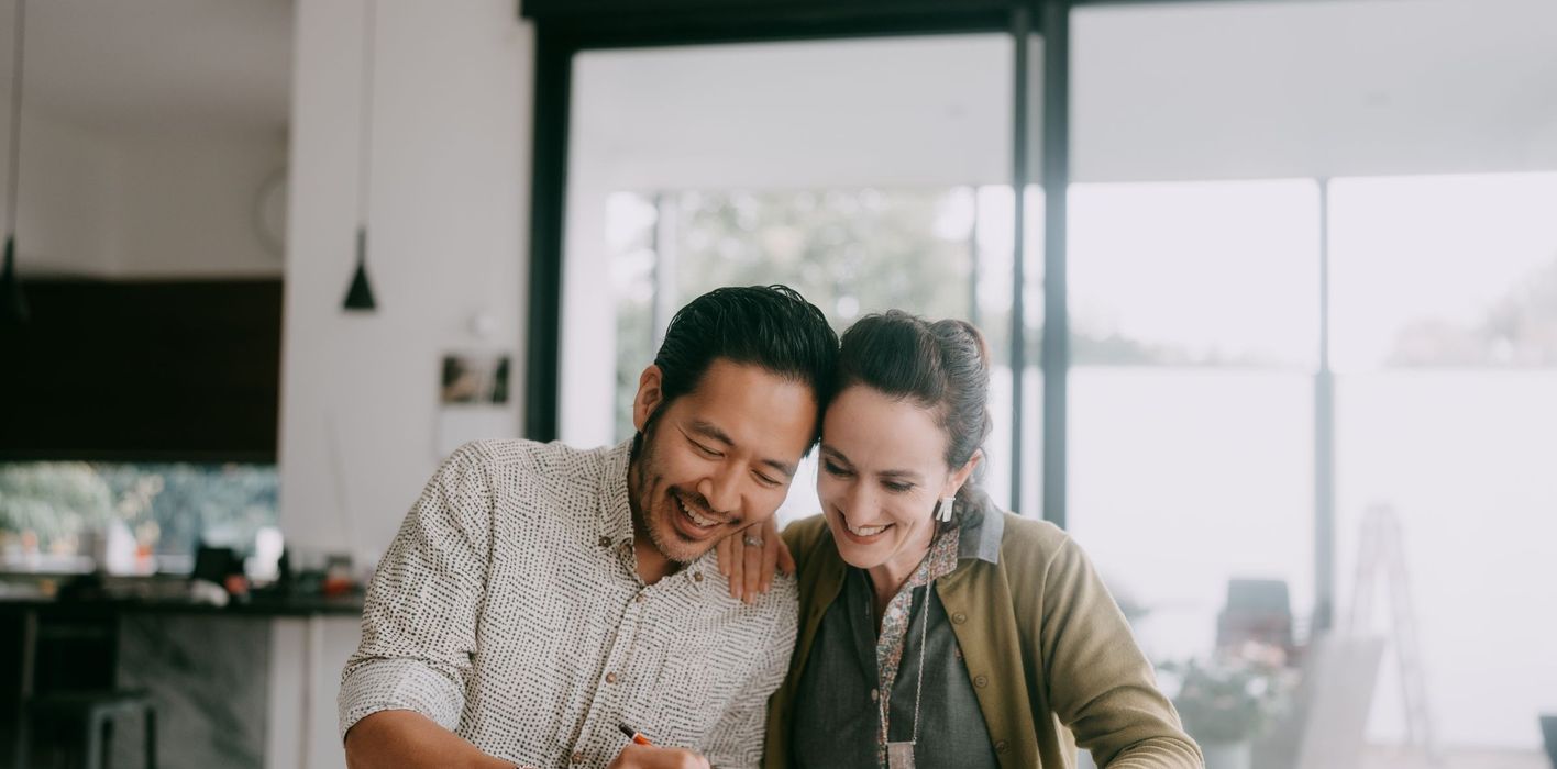 Cheerful couple looks at paperwork together in a kitchen