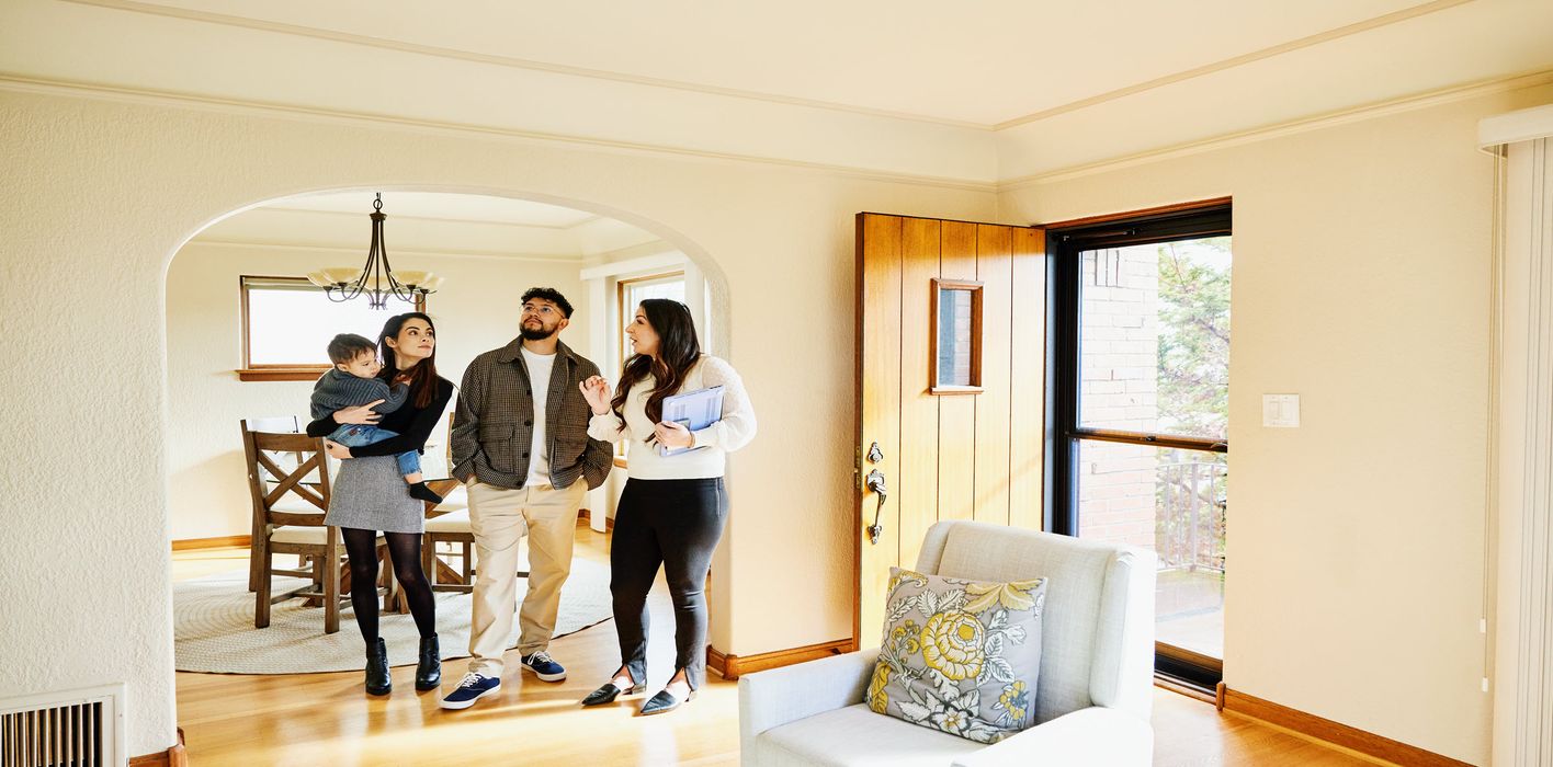A couple, their toddler, and realtor standing in the foyer of a new home
