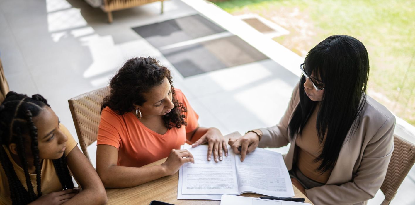 Female professional consultant talking to a mother and daughter during a home visit 
