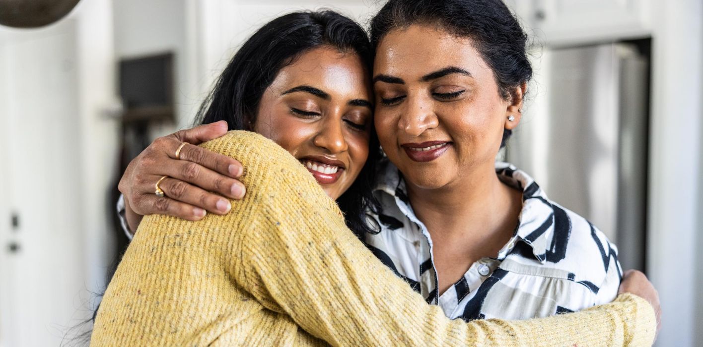 Mother embracing adult daughter at home