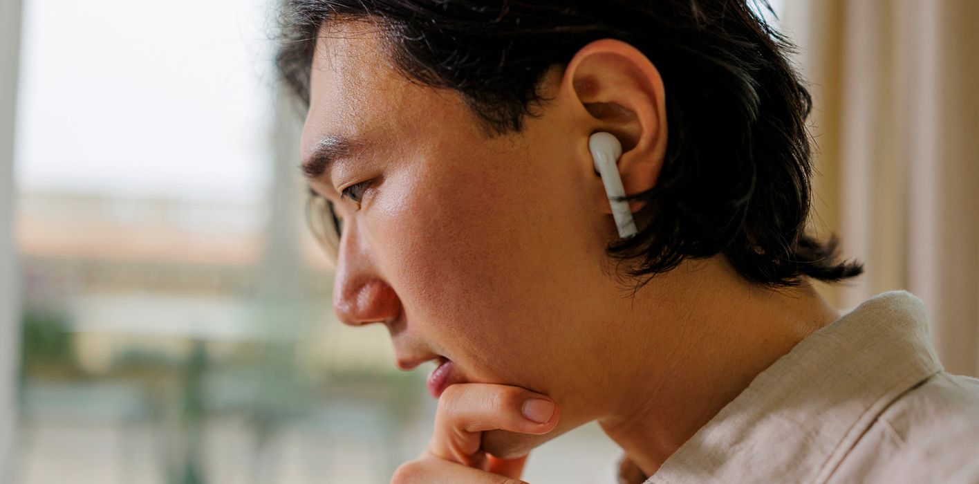 Focused office worker wearing earbuds at office, contemplating stock market moves and reading Northwestern Mutual Weekly Market commentary.