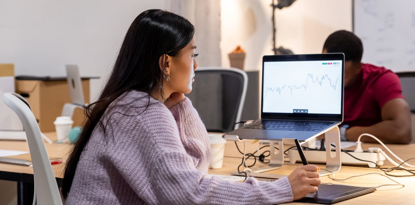 Woman tracks economic and market movements on her computer in a modern office.