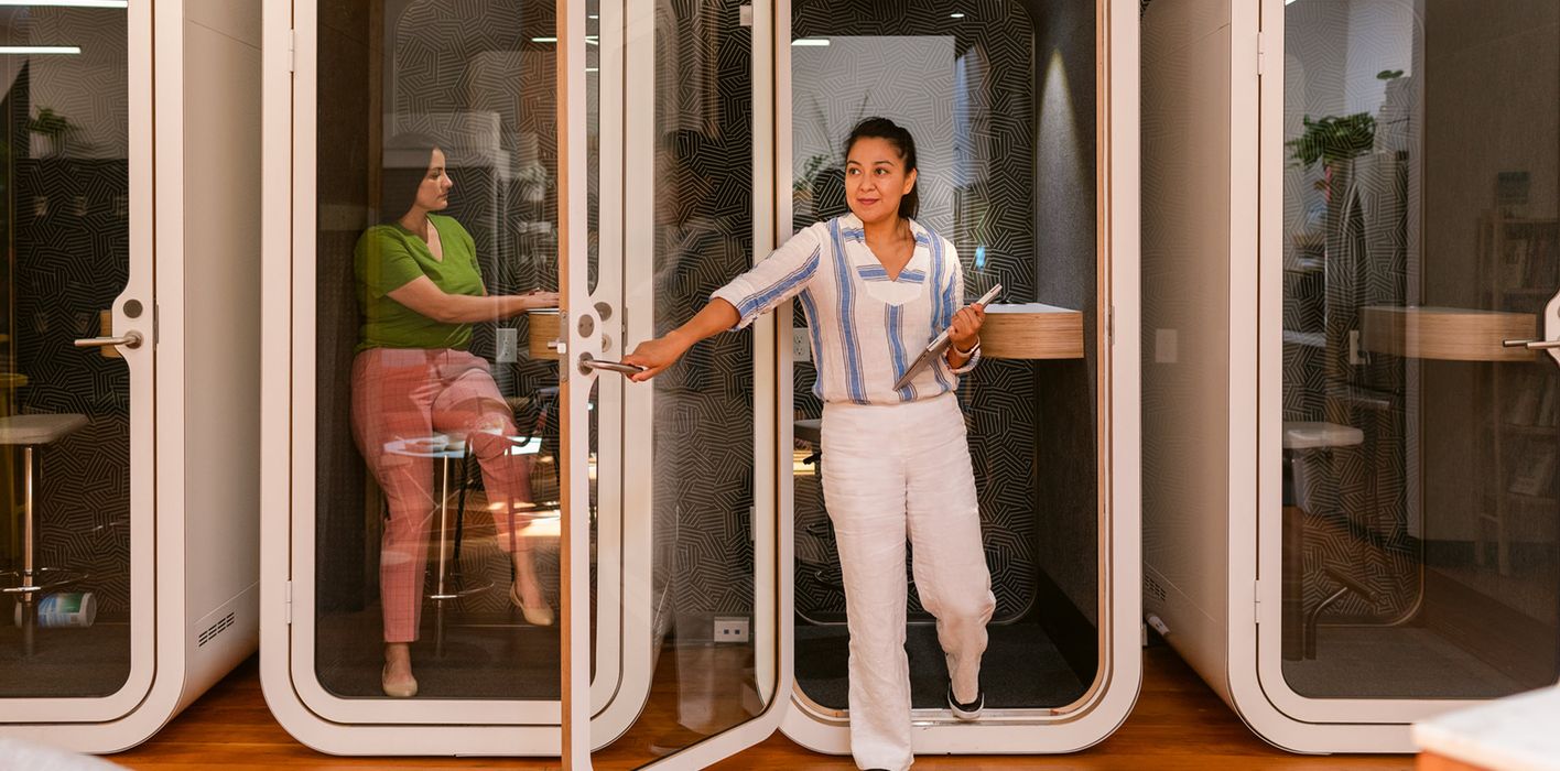Co-workers use private booths in modern office