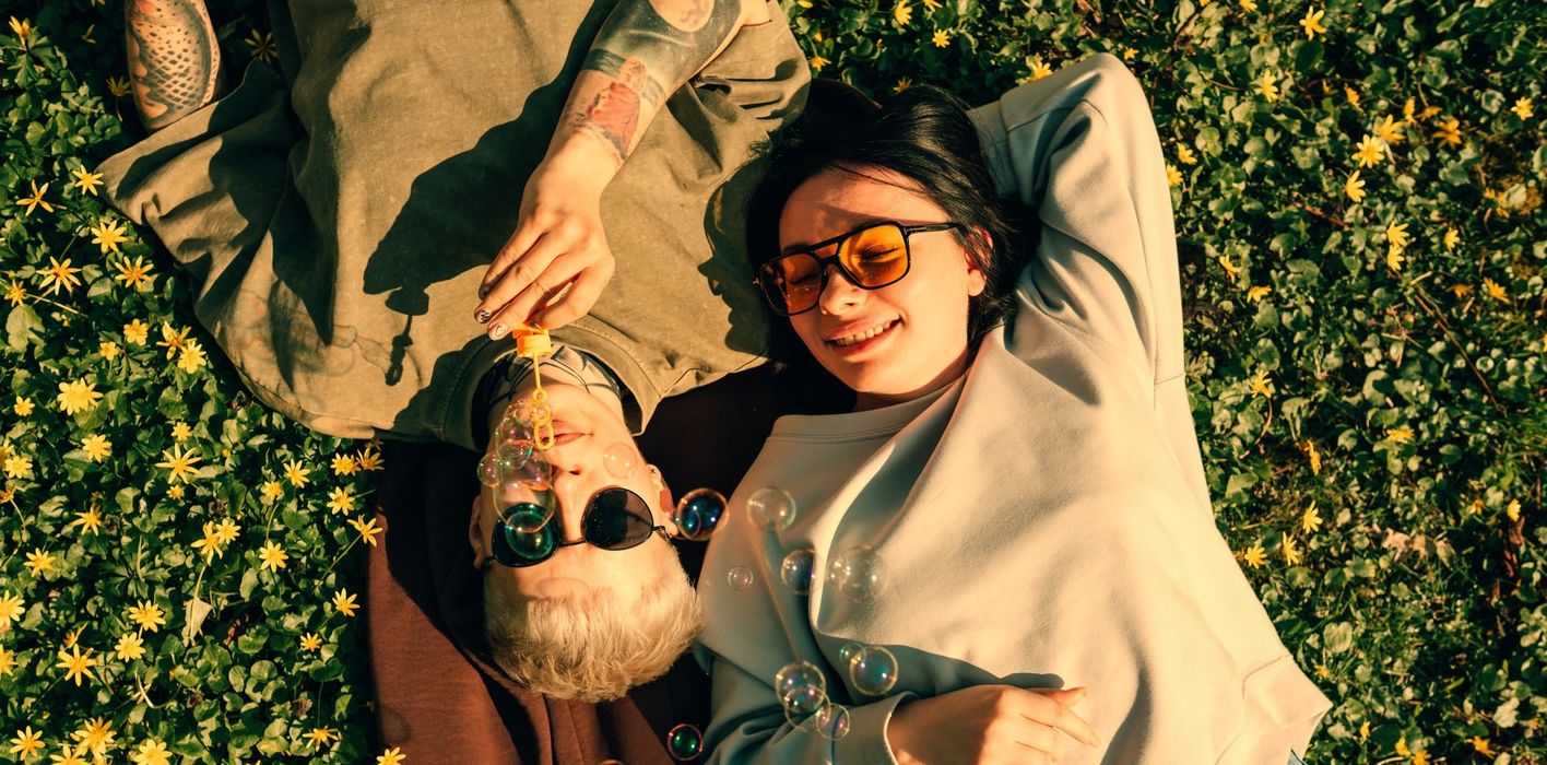 Young couple lying on grass blowing soap bubbles 