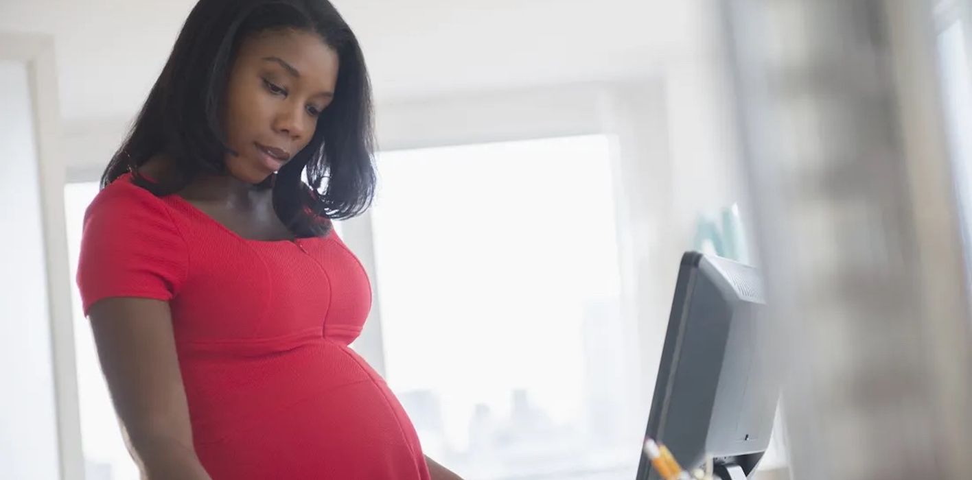 Pregnant woman on the computer with papers