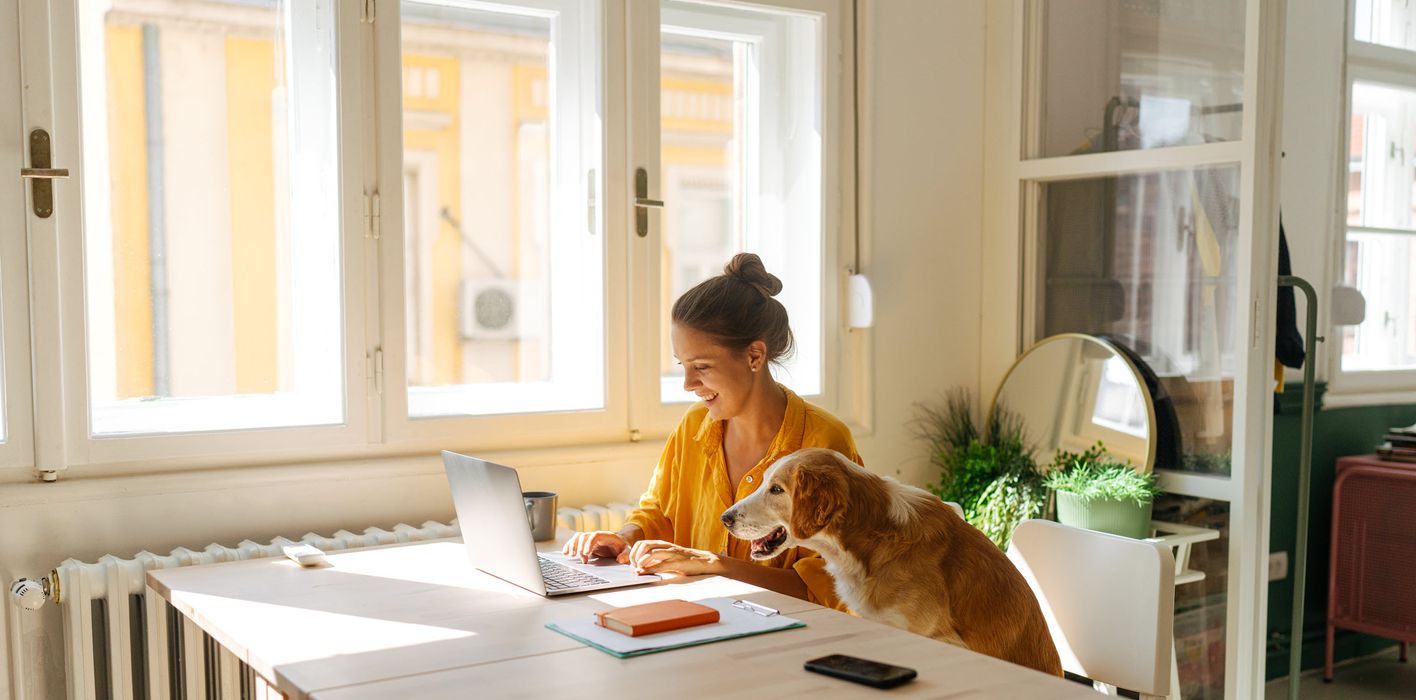 Woman reading Northwestern Mutual’s Weekly Market Commentary alongside her dog.