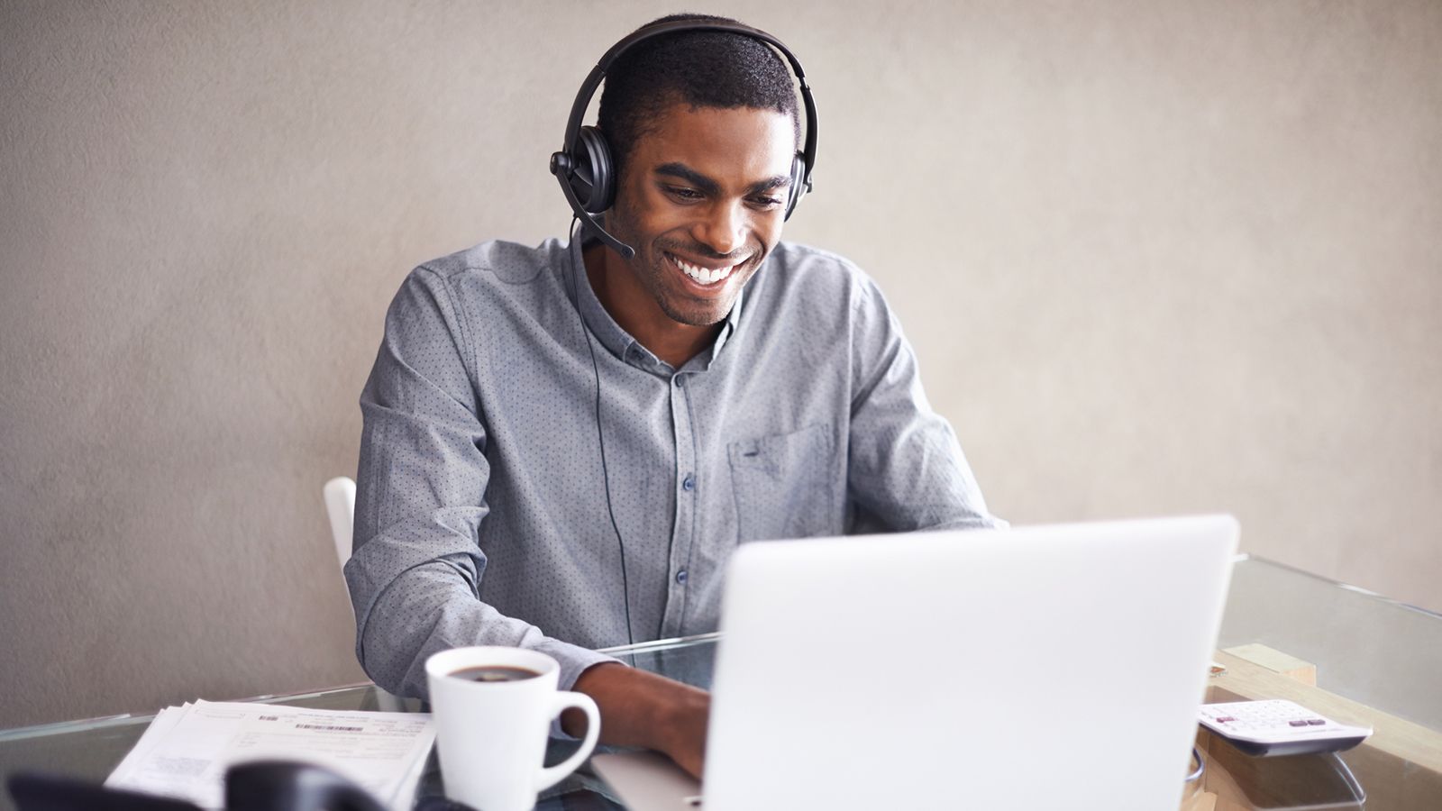 young man wearing a headset while working on his laptop