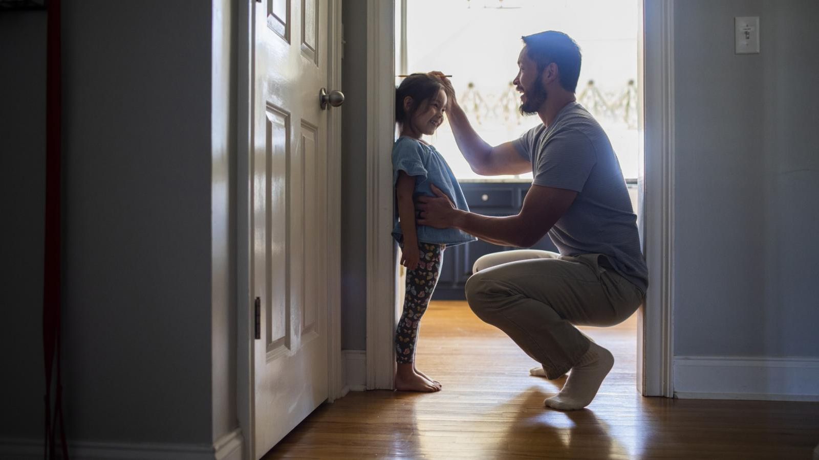 Father checking height of daughter whom he wants to protect as a life insurance beneficiary.