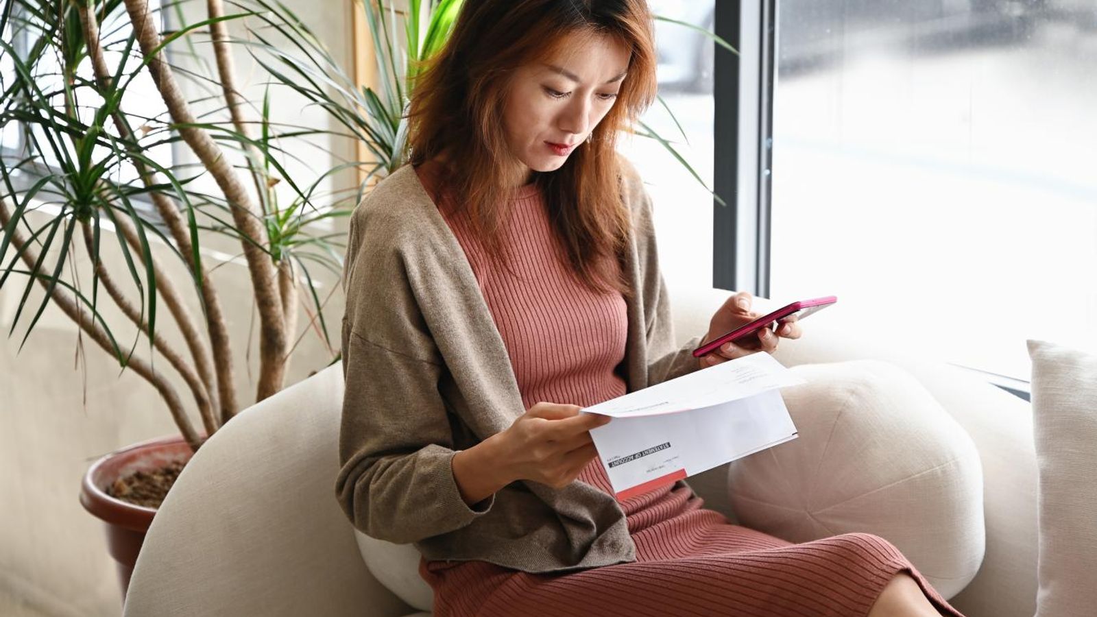 Woman checking her bank statements on a sofa