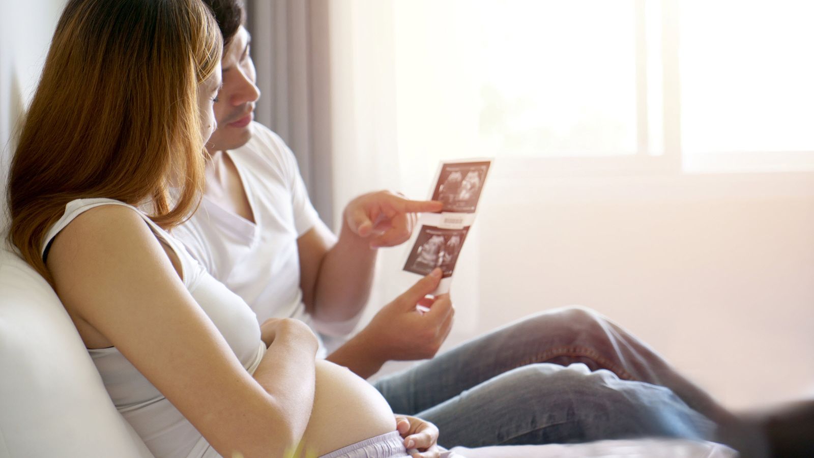 Couple looking at ultrasound pictures and discussing pay on maternity leave