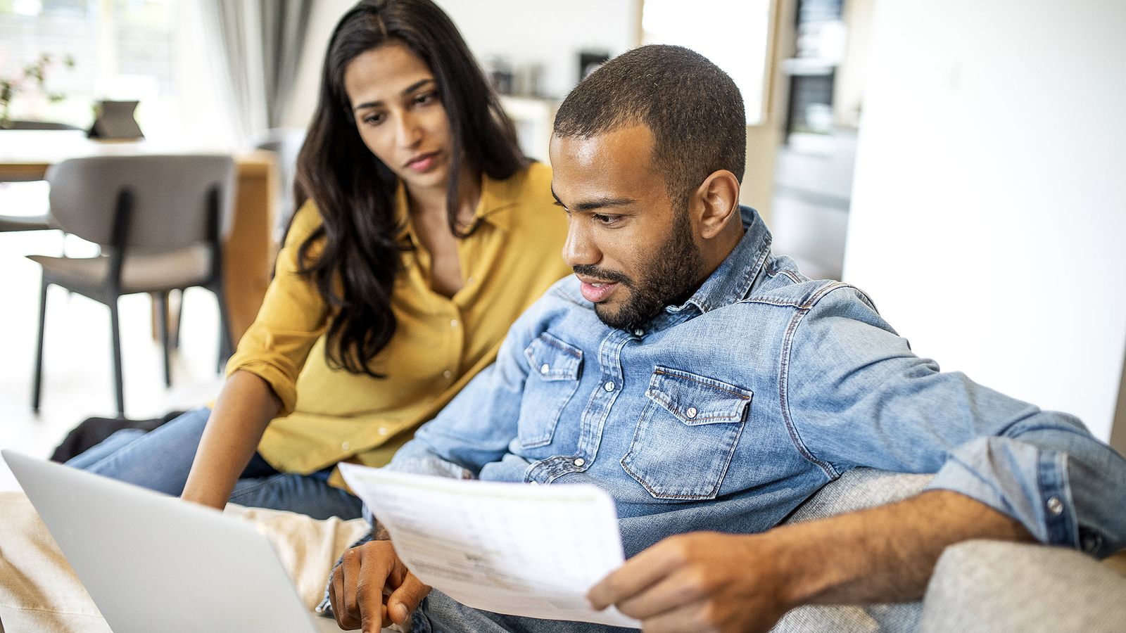 couple looks through bills and works on a laptop