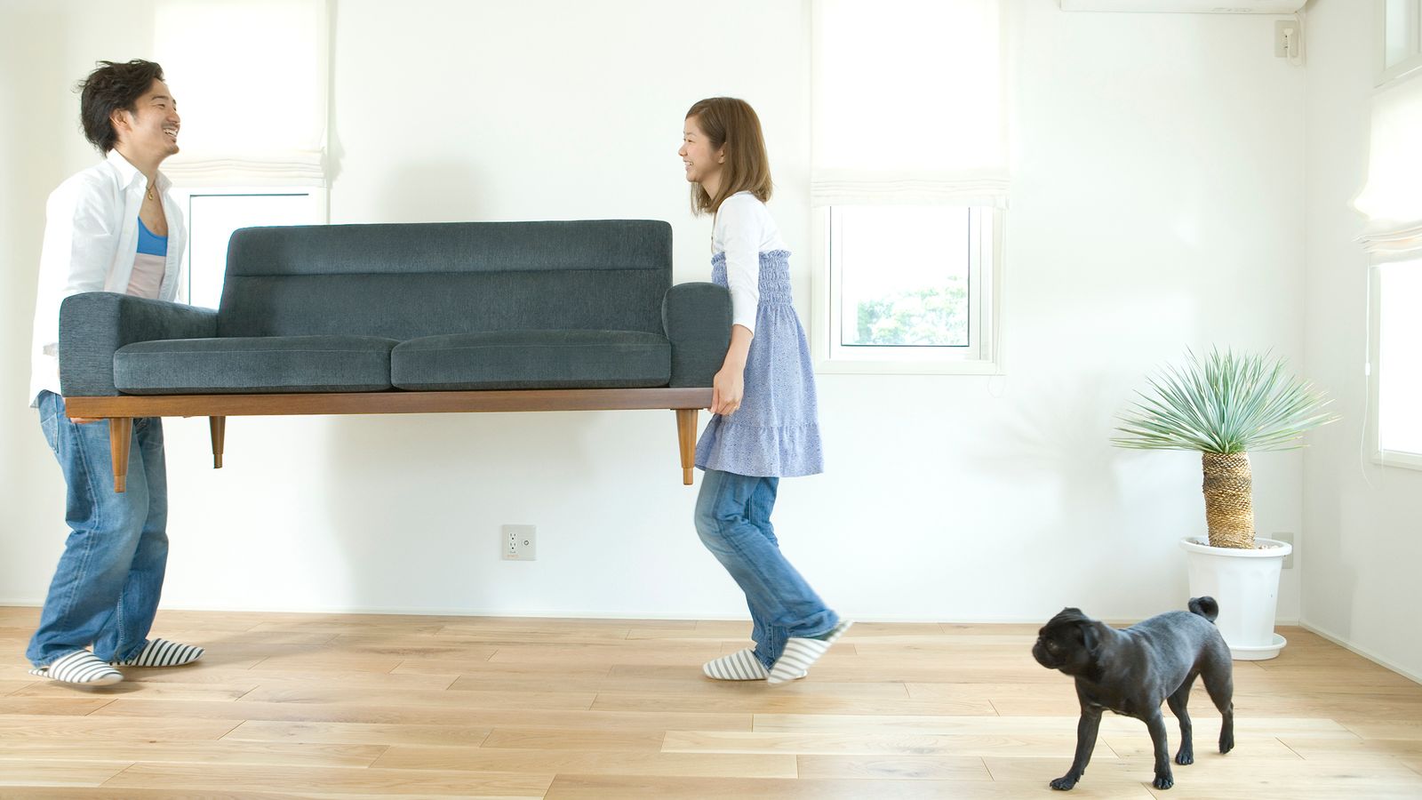 Couple carrying a couch into a new home