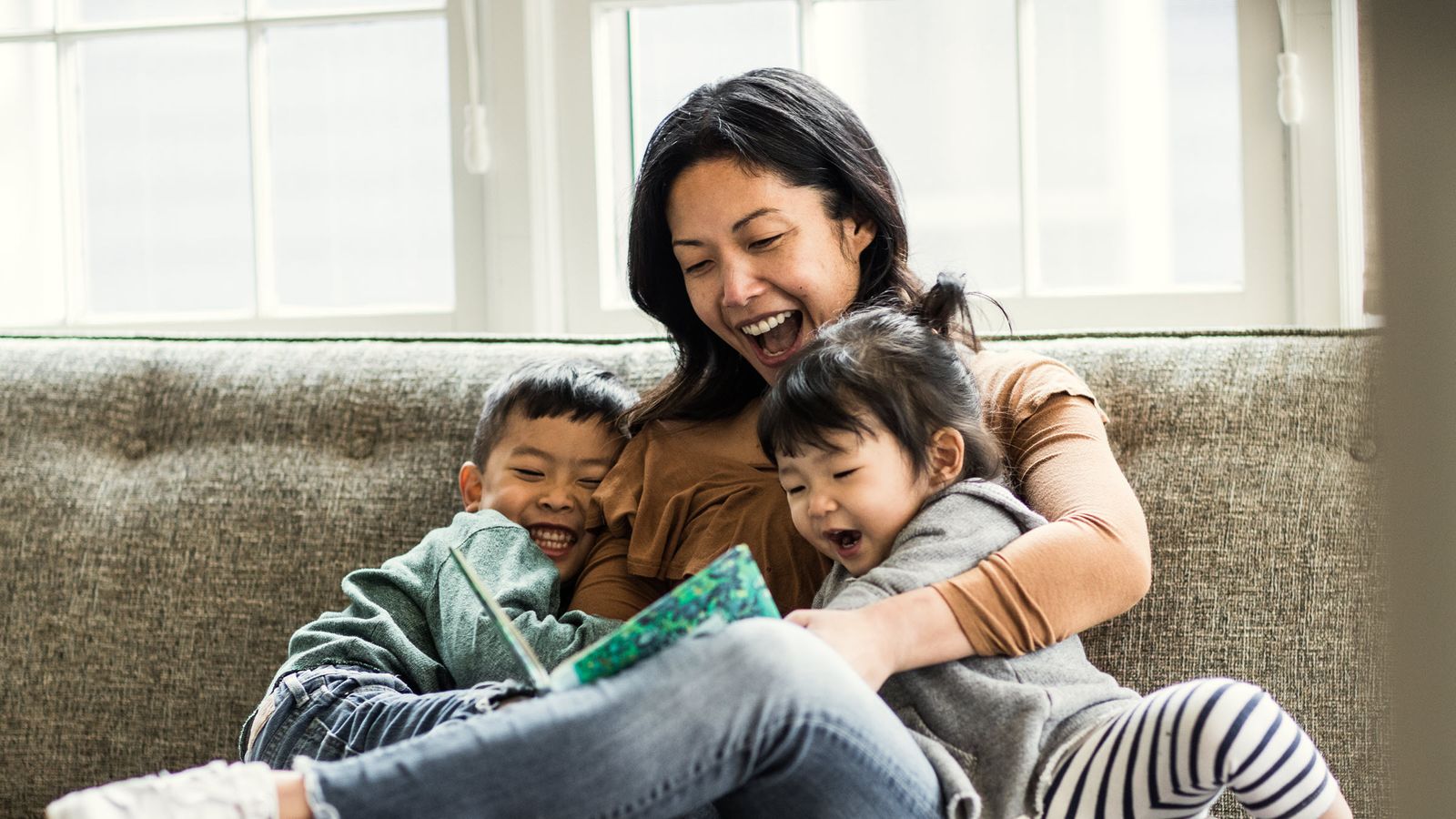 Mom on a couch reading with her kids.
