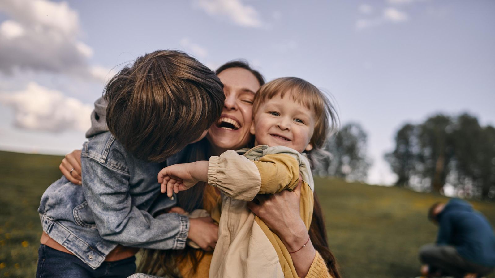 Happy mother hugging sons on a meadow