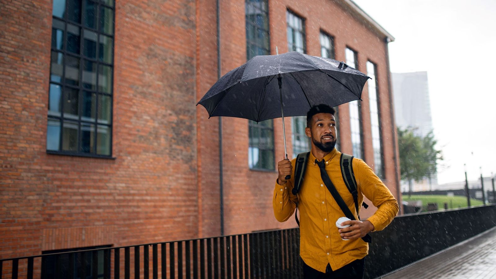 A man walking to work in the rain with an umbrella