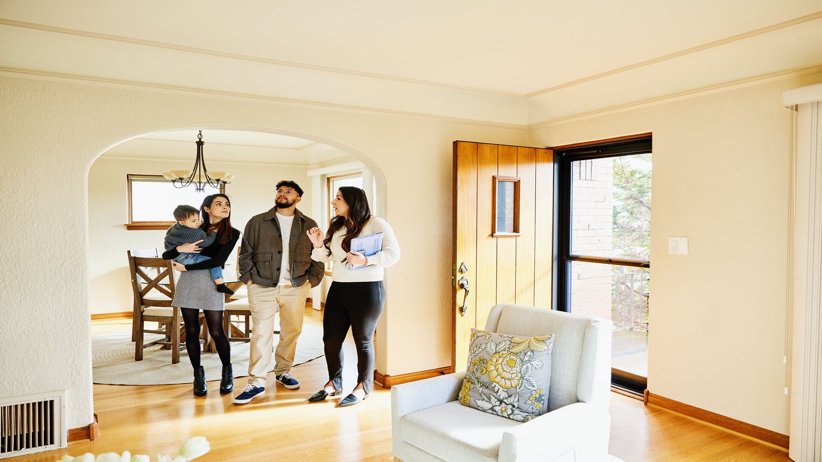 A couple, their toddler, and realtor standing in the foyer of a new home
