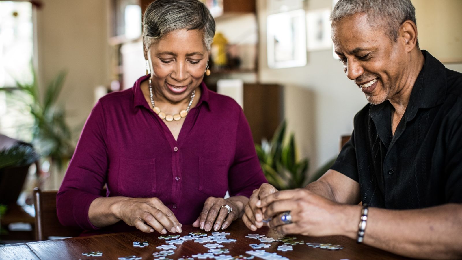 Two 60-year-olds assemble a puzzle at home.
