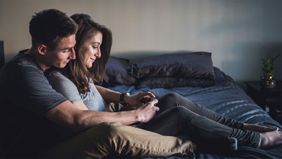 Couple sitting on the bed discussing joint bank accounts