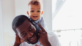 Dad with son on shoulders wondering how much it costs to have a baby
