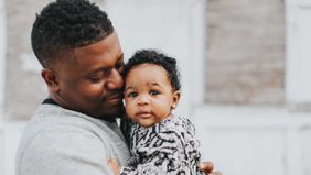 Dad holding baby thinking about surprise parenting costs