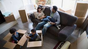 Family surrounded by moving boxes talking about furnishing a new home
