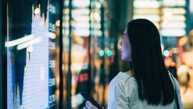 A young woman checking out stock charts from the street