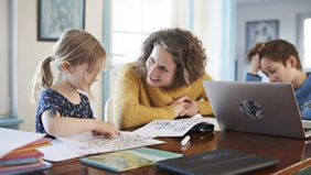 Mother home schooling daughter and son at table 