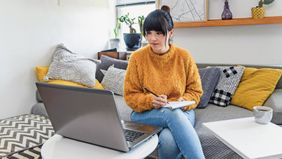 woman sitting on couch working on laptop