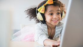  smiling girl wearing headphones while using laptop