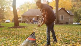 man raking leaves in backyard 