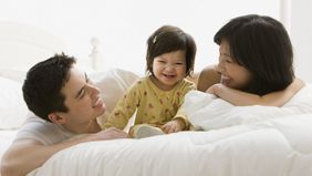 Couple on a bed with their child after discussing how term life insurance works.