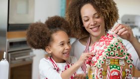 mother and daughter decorating gingerbread house