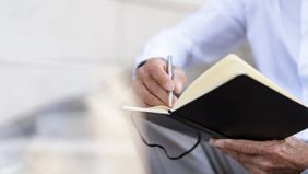Man writing in a journal as he goes through an end of life checklist.