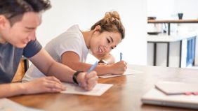Couple writing personal letter to home seller.