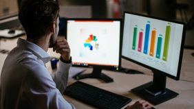 man studies markets on computer