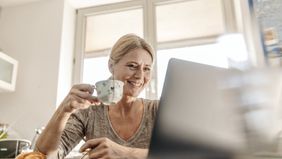Woman drinking coffee and reading Northwestern Mutual Market Commentary