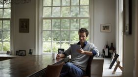 Man sitting at a table and reading Northwestern Mutual Market Commentary