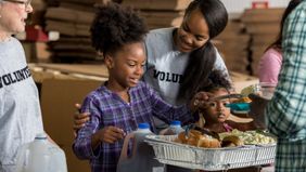 Mom and daughter volunteering teaching kids to be generous